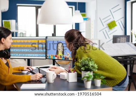 Art director consulting designer colleague, retouching portrait in photo editing software working in creative agency. Retouchers talking, color grading assets using graphic tablet with stylus pen