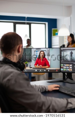 Video editor talking with remote customer in web online meeting using video call editing project, getting feedback on commercial movie using post production program on two displays in creative agency