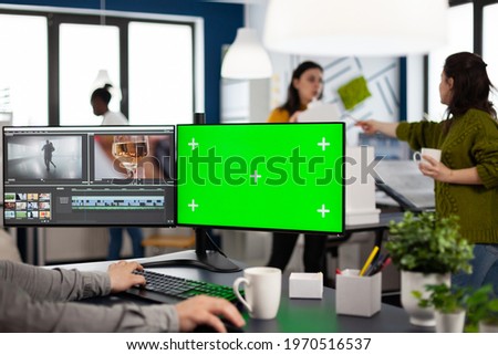 Video maker editing movie using post production software working in creative agency at pc with green screen, chroma key, mock up isolated display. Videographer processing audio film montage