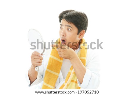 A man looking at himself in a hand mirror