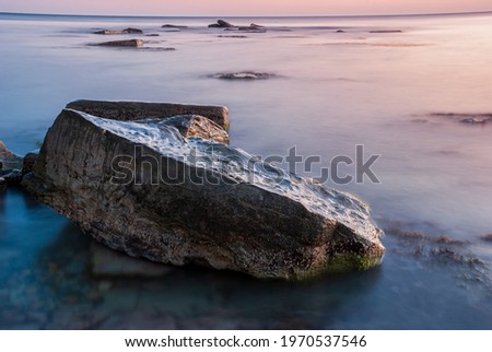 Seascape at sunset. Sea on a long shutter with stones and rocks.