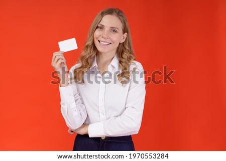 Portrait of a young beautiful woman holding empty business card isolated over orange background