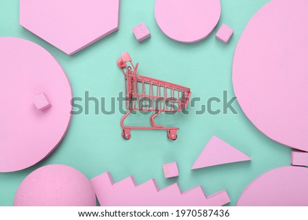 Creative shopping layout. Pink supermarket trolley with pink different geometric shapes on mint blue background. Pastel color trend. Minimalism. Concept art. Flat lay. Top view.