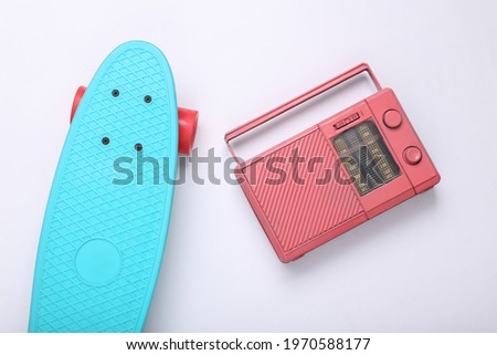 Pink radio receiver and penny board on white background. Creative hipster layout. Minimal concept. Top view. Flat lay