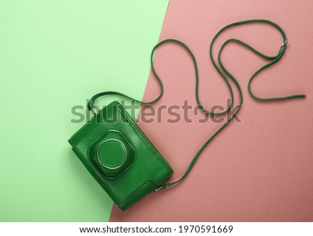 Retro camera in a leather case on green pink background. Top view