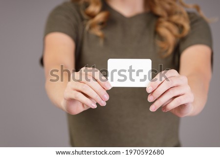 Girl holding white business card on gray background