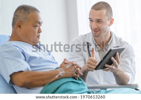happy asian elderly looking at a good result of health check up in the medical chart with doctor.