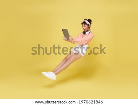 Young asian teenage girl hand holding computer laptop floating in mid-air isolated on yellow background. Fast internet concept. Royalty-Free Stock Photo #1970621846