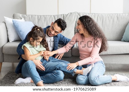 Portrait Of Happy Arab Family Spending Time Together At Home, Cheerful Middle Eastern Parents Having Fun With Their Daughter, Tickling Little Child And Laughing, Enjoying Domestic Leisure, Free Space Royalty-Free Stock Photo #1970625089
