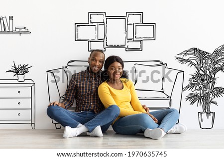 Happy Black Spouses Imagining Interior Of Their New Flat, Sitting On Floor Near White Wall With Doodle Drawings, Young African American Couple Planning Relocation, Creative Collage Royalty-Free Stock Photo #1970635745