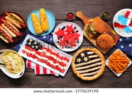 Fourth of July, patriotic, American themed food. Above view table scene on a dark wood background.