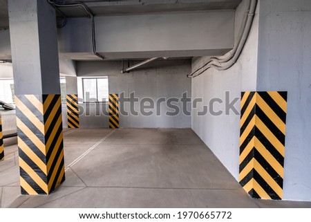 An empty underground garage, yellow-black striped posts, gray walls