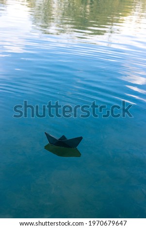 Black paper boat floats on the river