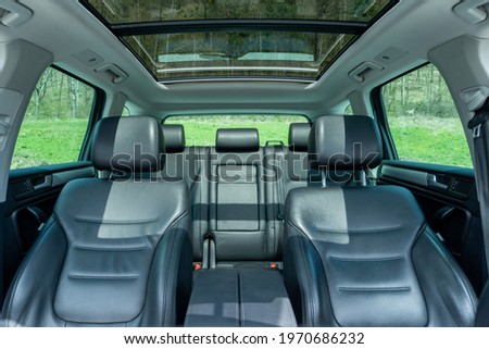 Panoramic view inside car - double sunroof hatch with tinted glass. Sliding panoramic sunroof and luxurious leather seats. Close up photo with bright blue sky seen through sunroof. Royalty-Free Stock Photo #1970686232