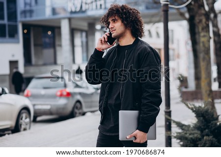 Handsome student with curly hair using laptop
