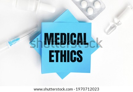 On a white background, a syringe, ampoule, pills, a vial of medicine and light blue stickers with the inscription MEDICAL ETHICS. Medical concept