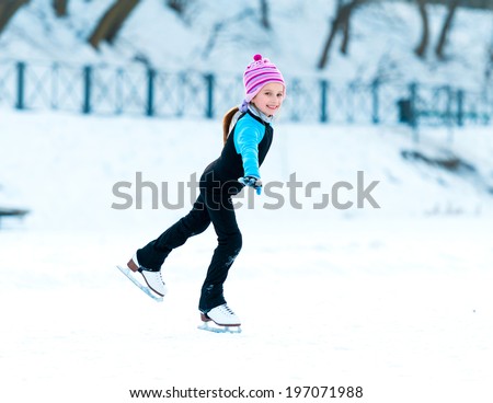 cheerful happy little girl in thermal suits skating in winter outdoors