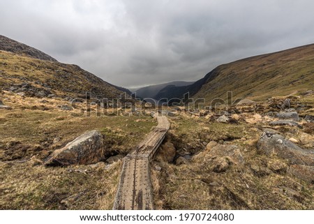 photography of mountainous landscape with wooden path and a lake in the background in Glendalough Wicklow Ireland