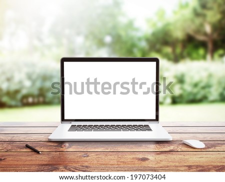 Laptop stands on a wooden table outdoors