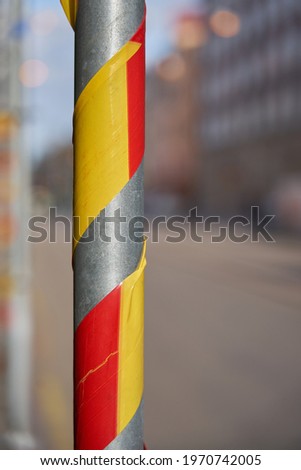 A pillar with a building warning tape on the street.