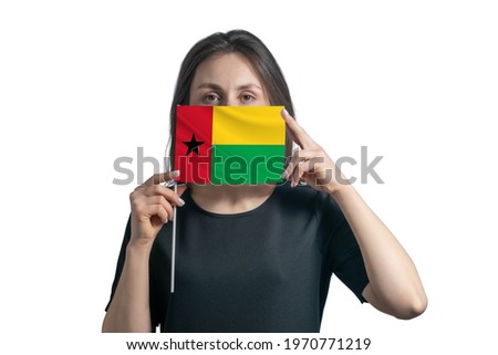 Happy young white woman holding flag Guinea-Bissau flag and covers her face with it isolated on a white background.