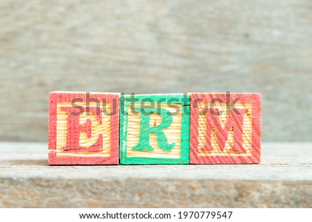 Color alphabet letter block in word ERM (Abbreviation of Enterprise risk management) on wood background