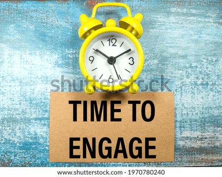 Business concept.Text TIME TO ENGAGE with clock on blue wooden background. Royalty-Free Stock Photo #1970780240