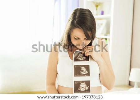 Beautiful pregnant woman holding ultrasound scan picture