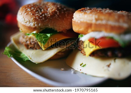 Photos of homemade burgers. Steak and white bun with sesame seeds, cheese and cabbage, tomatoes. Homemade food.