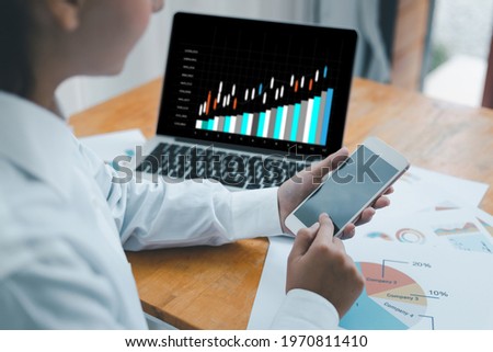 Businesswoman using smartphone for investment consultant analyzing company financial report balance sheet statement working with blurry of screen documents graphs. Concept picture for stock market.