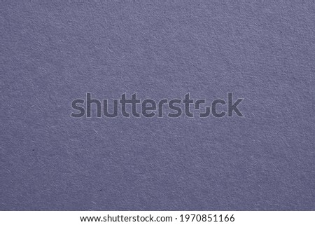 The surface of purple blue cardboard. Grey paper texture with cellulose fibers. Generic gray tinted background. Dark summer paperboard wallpaper. Top-down. Macro
