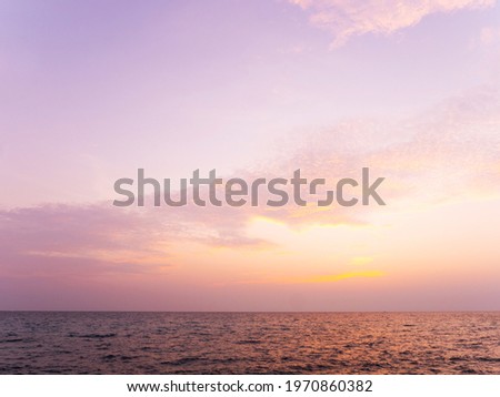 Peaceful serene sea scape and golden purple tone sunset or sunrise sky with clouds, tropical island ocean view at dawn or dusk