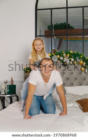 Young happy dad and little daughter on the new year's bed.