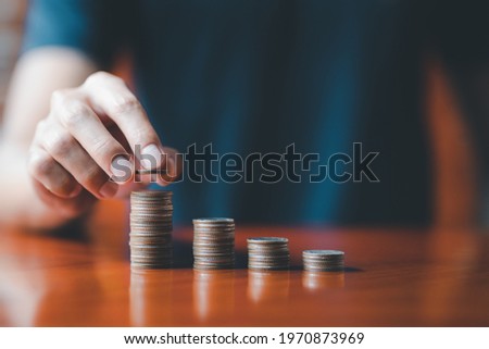 Closeup man hands. Businessman holding coin to place on stack of coins placed on the table. Accounting, Financial investment, saving money for future growth concept.