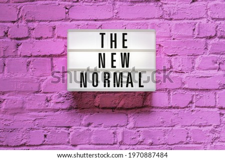 The new normal sign hanging on brick wall. Signboard message about opening after quarantine. Start new normal. Text Back to normal on lightbox.