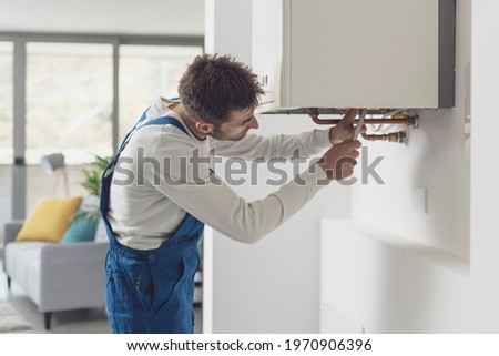 Professional plumber checking a boiler and pipes, boiler service concept Royalty-Free Stock Photo #1970906396