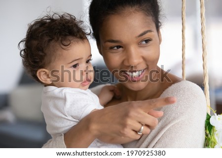 Close up of happy young African American mom hold cute little baby daughter play together at home. Smiling loving ethnic mother cuddle hug small biracial toddler kid child. Parenthood concept.