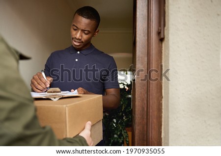 Young African man signing a clipboard for a delivery