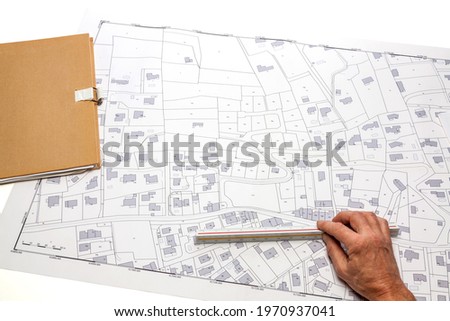 Town planning and land use planning - hand holding a measuring ruler on a cadastral map placed on a desk  Royalty-Free Stock Photo #1970937041
