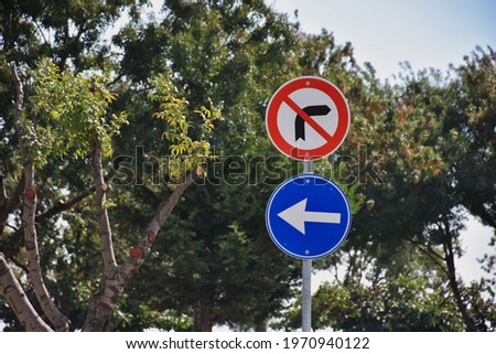 traffic signs standing in front of trees in the park