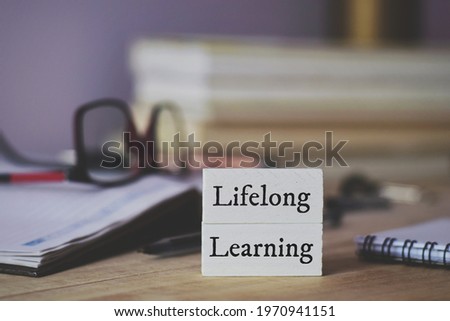 Lifelong Learning Education concept written in painted wooden chips on office desk with defocused faded background. Royalty-Free Stock Photo #1970941151
