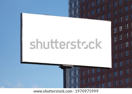 Horizontal blank billboard against the background of a residential skyscraper and the sky during the day. Mock up.