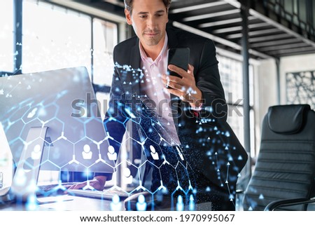 Businessman in suit using smart phone to check new candidates for international business consulting. HR, social media icons over modern panoramic office background.