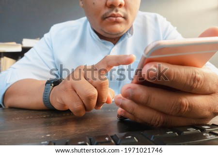 person hand using a device for communication in his desk. Mobile phone for fun and entertainment. Man using modern gadgets. Technology and mobile addiction concept.