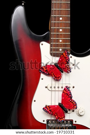 closeup on electric guitar and fake red butterflies, black background
