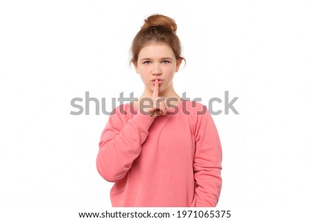 young girl 12-14 years old keeping index finger near mouth making hush sign, say shhh, isolated on white background. Secret, expression and emotion concept