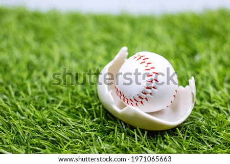 Baseball in egg shell is on green grass  for Easter Holiday