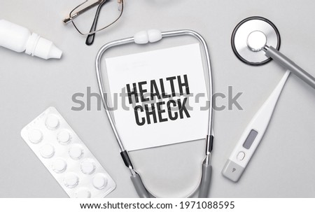 In the notebook is the text health check, stethoscope, pills, and glasses.
