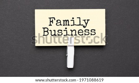 FAMILY BUSINESS text on paper with wihte clip. On black background