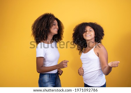 afro mother and daughter dancing on yellow background
